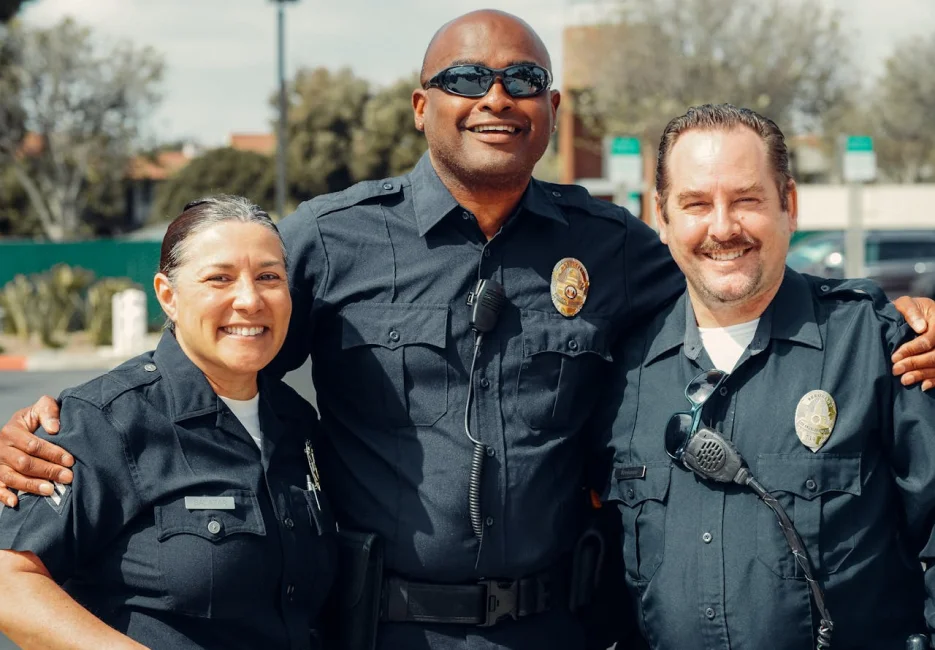 two police men and a police woman smiling at the camera